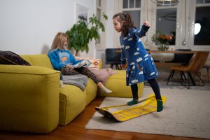 two kids using a giboard (similar to a skateboard with no wheels and a slackline on top)