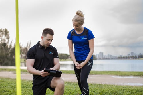 Certified personal trainer guiding a client during a workout session.