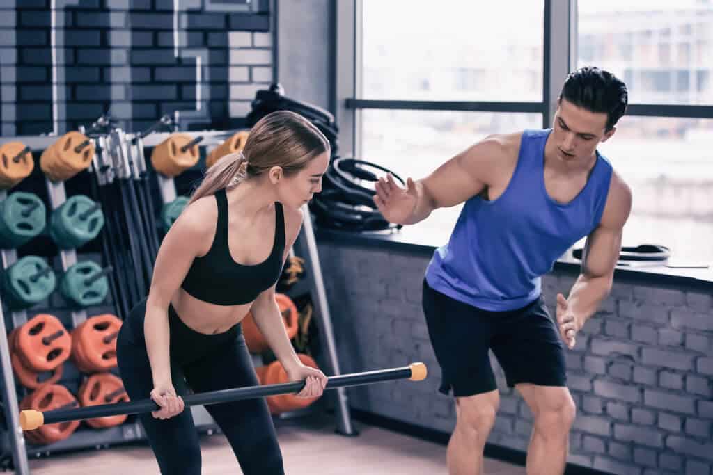 Right personal trainer teaching proper form to avoid injuries.
