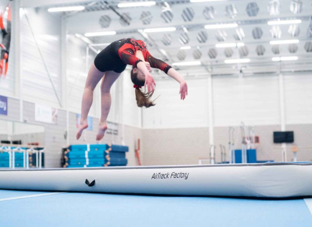 Professional gymnast using an AirTrack for muscle conditioning and home gymnastics training, emphasizing safe, effective balance training.