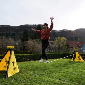 a woman walking on a slackline using slackframe instead of trees