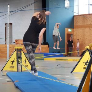 a woman balancing on a slackline in a school gym