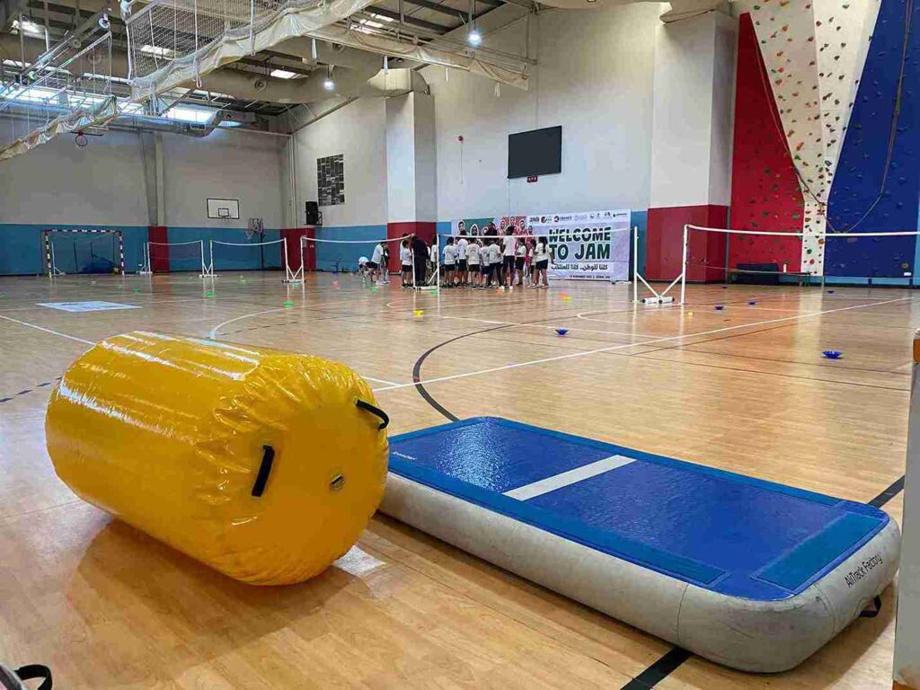 Group of children at a Dubai gymnastics event with an AirTrack mat and AirRoll, preparing for a workshop.