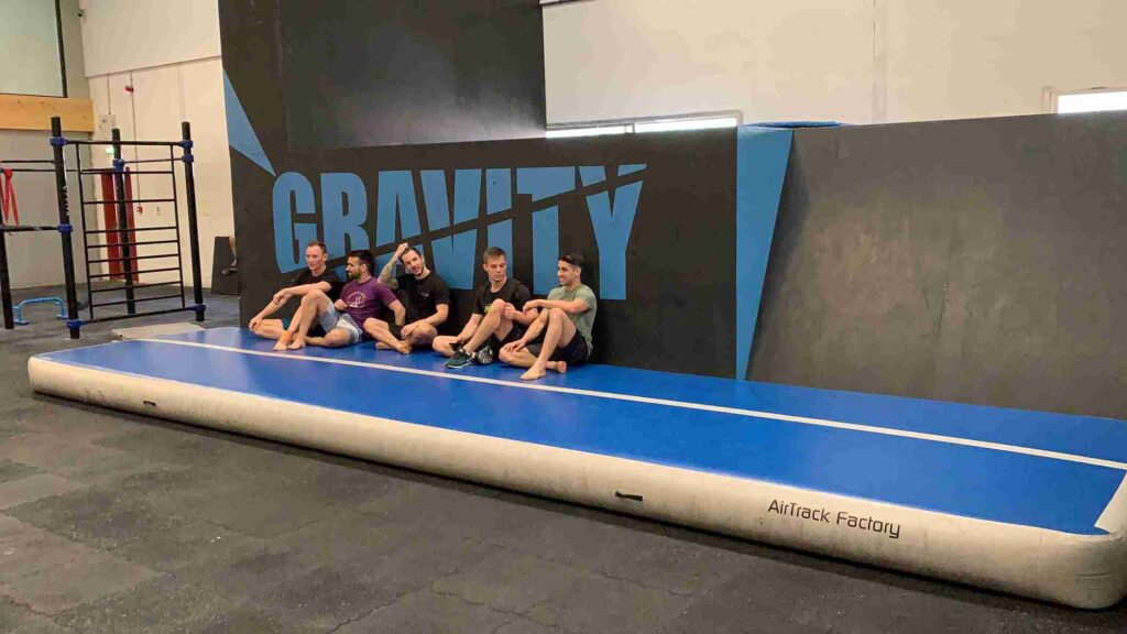 Gravity DXB team sitting on an AirTrack P3 mat during a calisthenics session in Dubai gym.