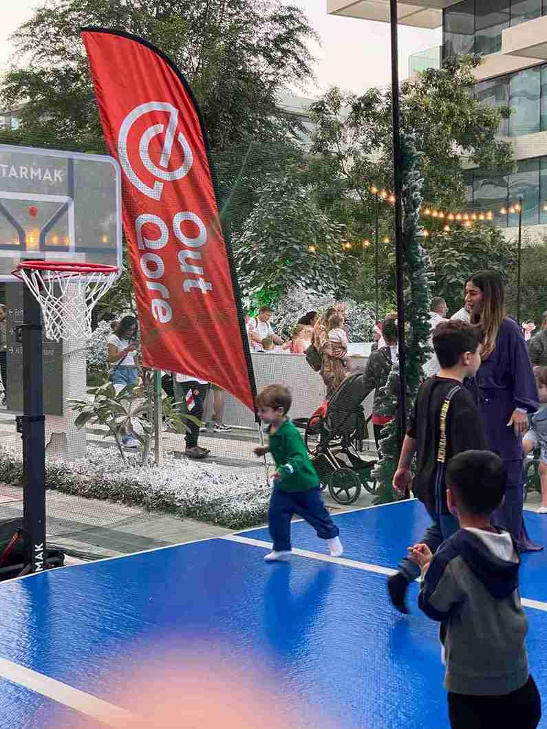 Kids playing on an AirTrack mat at an OutQore outdoor event in Dubai with a basketball hoop.
