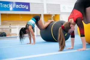 a woman doing push ups on a large black cylinder