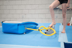 a person's leg on a foot pump inflating airtrack