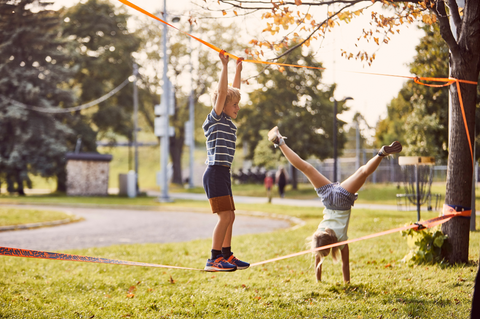 Overstimulated kids movement activity: children playing on slackline outdoors